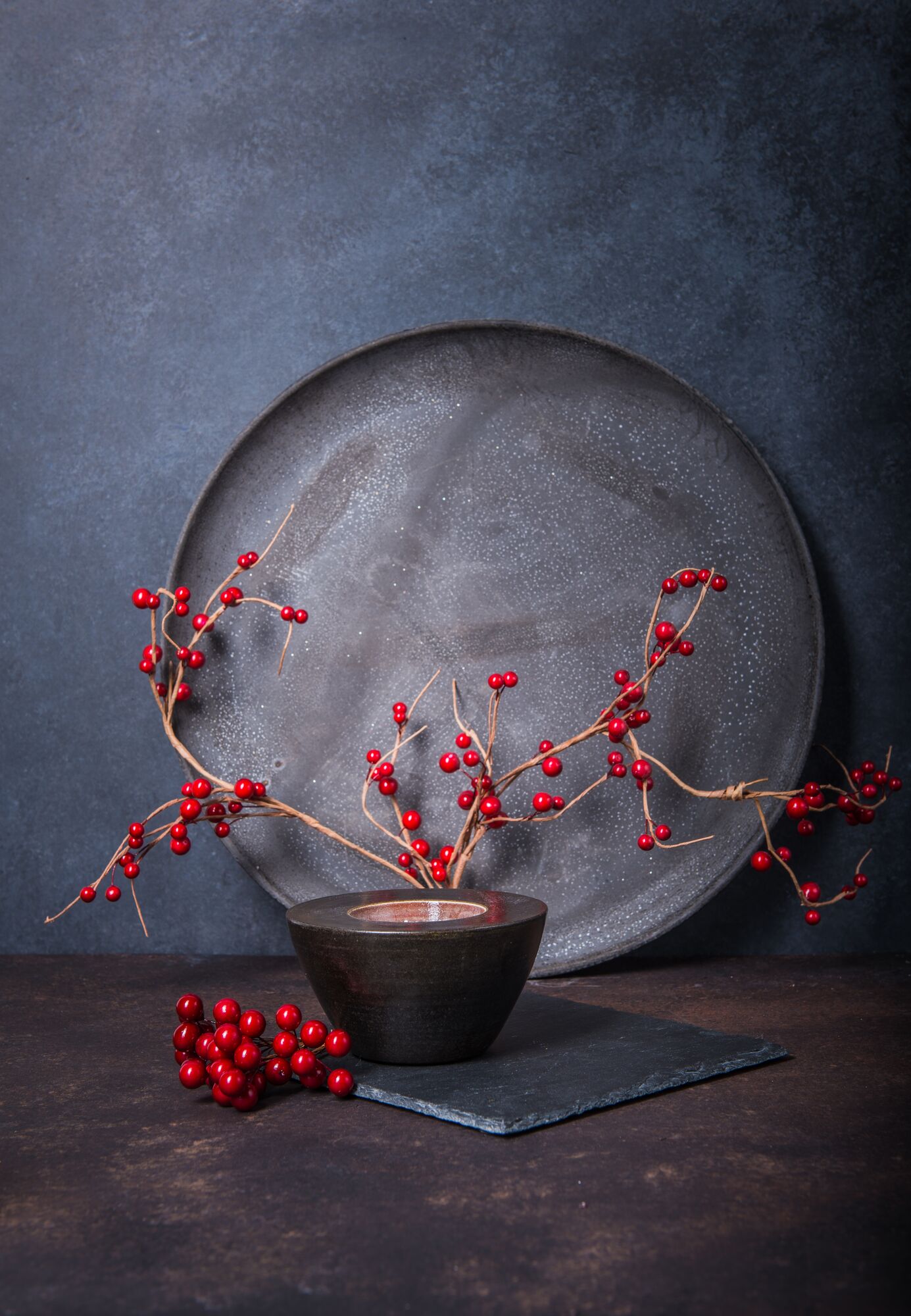 Stillleben mit roten Beeren und dunkler Schale